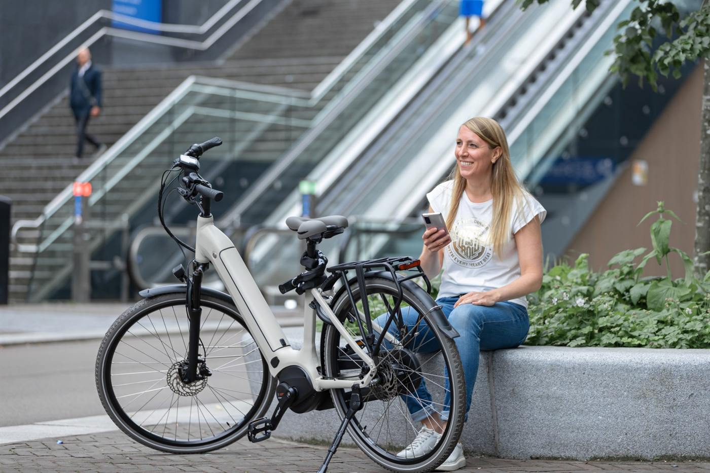 Een vrouw met een e-bike bij een trap in de stad