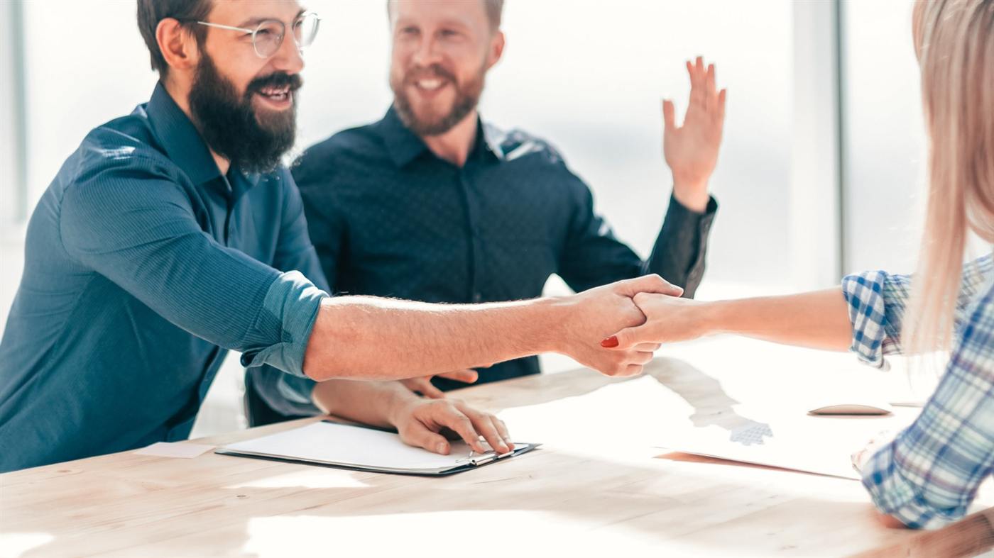 Een sollicitant schudt de hand van twee nieuwe collega's